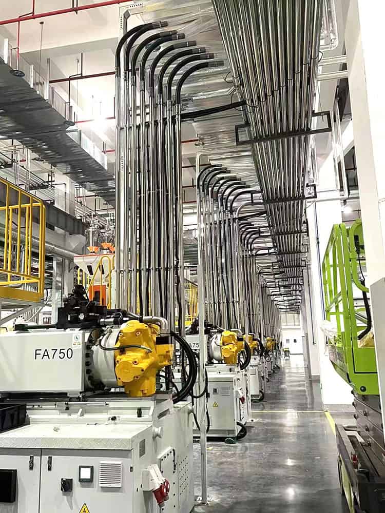 Schematic diagram of vacuum pipe routing in a central feeding system, connecting the main line to branch lines above injection molding machines.