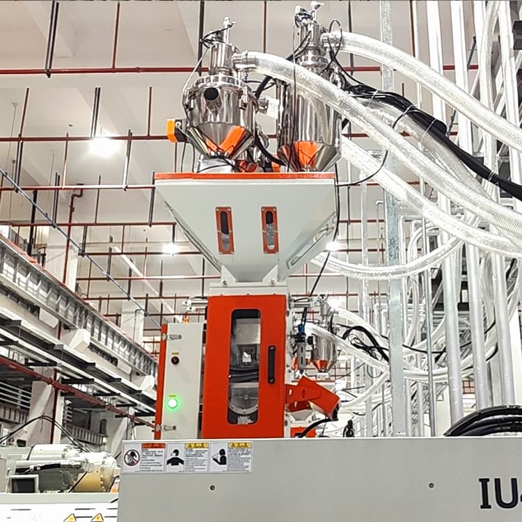 Gravimetric blender mounted on top of an injection molding machine for precise mixing of plastic materials by weight.