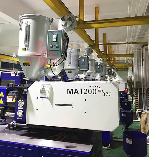 Hopper dryer installed on top of an injection molding machine for drying plastic raw materials before processing